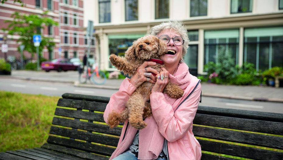 Dame hebt Hund auf Parkbank hoch